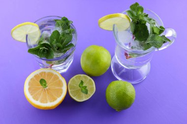 Mojito ultraviyole bir arka plan, nane, limon ve kireç, yaz dinlenmek için bir meşrubat, mor bir arka plan, bir pop sanat içki, yarım limon ve kireç, minimalizm kokteylde bir kokteyl