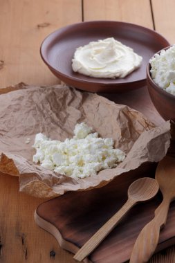 Peynir, peynir ve krem kil tencere, ahşap arka plan üzerinde taze peynir, ekşi krema rustik tarzı, sağlıklı gıda, Fransız Kahvaltı, üstten görünüm, parşömen kağıt, protein üzerinde keçi peyniri