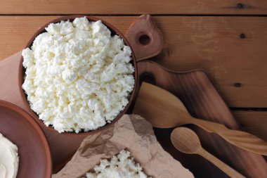 Peynir, peynir ve krem kil tencere, ahşap arka plan üzerinde taze peynir, ekşi krema rustik tarzı, sağlıklı gıda, Fransız Kahvaltı, üstten görünüm, parşömen kağıt, protein üzerinde keçi peyniri