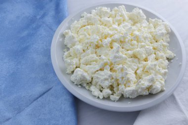 Peynir, peynir beyaz tabak, beyaz ve mavi peçeteye taze peynir, beyaz arka plan, sağlıklı gıda, Fransız Kahvaltı, üstten görünüm, keçi süt ürünleri lor minimalist tarzda, protein