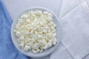 Peynir, peynir beyaz tabak, beyaz ve mavi peçeteye taze peynir, beyaz arka plan, sağlıklı gıda, Fransız Kahvaltı, üstten görünüm, keçi süt ürünleri lor minimalist tarzda, protein