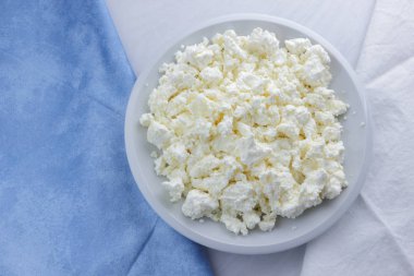 Peynir, peynir beyaz tabak, beyaz ve mavi peçeteye taze peynir, beyaz arka plan, sağlıklı gıda, Fransız Kahvaltı, üstten görünüm, keçi süt ürünleri lor minimalist tarzda, protein