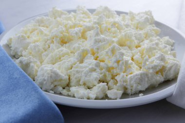 Peynir, peynir beyaz tabak, beyaz ve mavi peçeteye taze peynir, beyaz arka plan, sağlıklı gıda, Fransız Kahvaltı, üstten görünüm, keçi süt ürünleri lor minimalist tarzda, protein