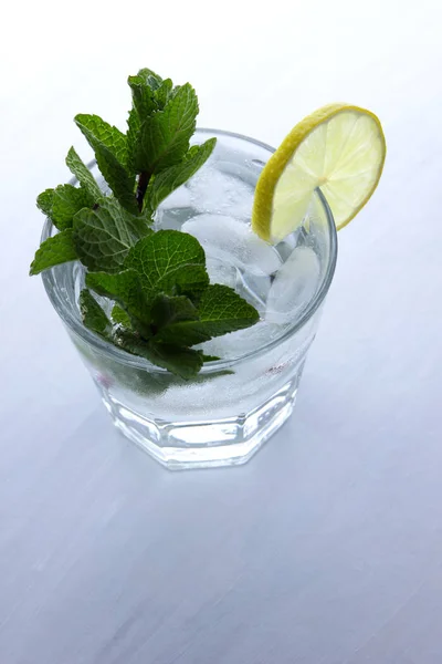 Cocktail with ice on a white background, mojito on summer vacation, a soft drink with lime and lemon, fresh mint for a cocktail, citrus for making a drink, minimalism, preparation for a designer
