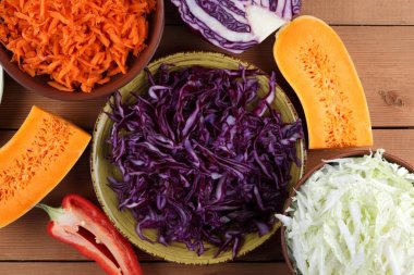 Çeşitli sebze ahşap arka plan, mor ve yeşil lahana, rendelenmiş havuç, dilimlenmiş kabak ve kırmızı biber, mor soğan yeşil bir tabak, sebzeli yemekler, sebze çok rustik içinde