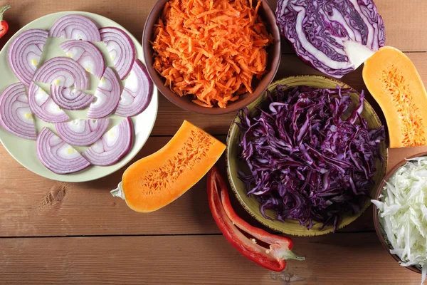 Çeşitli sebze ahşap arka plan, mor ve yeşil lahana, rendelenmiş havuç, dilimlenmiş kabak ve kırmızı biber, mor soğan yeşil bir tabak, sebzeli yemekler, sebze çok rustik içinde