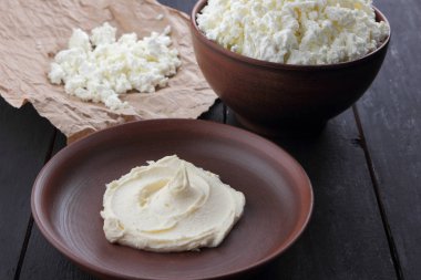 Peynir, taze peynir ve ekşi krema toprak, parşömen kağıt üzerinde keçi peyniri, rustik tarzı, sağlıklı gıda, ahşap bir zemin üzerine süt ürünleri alan, karanlık bir arka plan üzerinde süzme peynir kopyalamak minimalizm