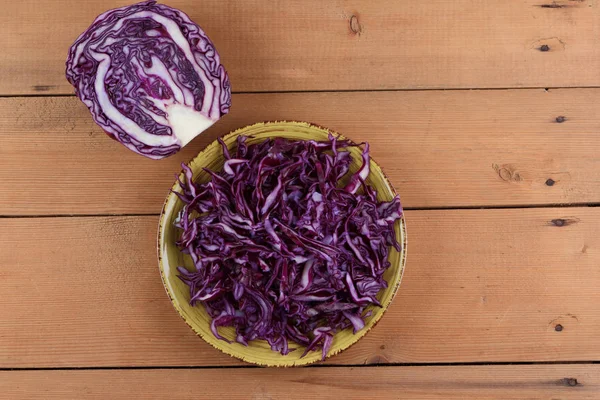 Chopped purple and green cabbage on a wooden background, cabbage on the plate, sliced cabbage in a minimalist style, rustic vegetables, a vegetarian product, vitamins, healthy food, art