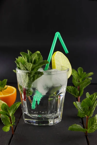 Mojito on a dark background, summer cocktail with lime and mint, refreshing drink with lemon, fresh mint for cocktail, celebratory drink with ice, copy space, minimalist cocktail