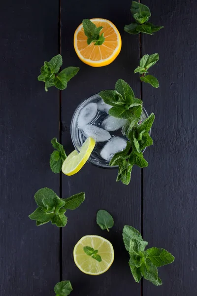 Mojito on a dark background, summer cocktail with lime and mint, refreshing drink with lemon, fresh mint for cocktail, celebratory drink with ice, copy space, minimalist cocktail