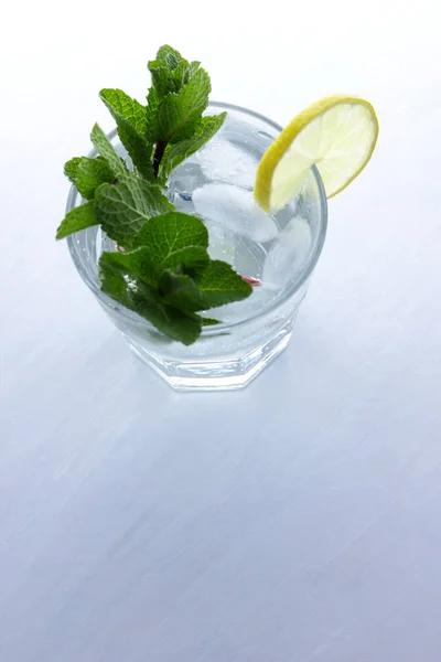 Mojito on summer vacation, cocktail with ice on a white background, a soft drink with lime and lemon, fresh mint for a cocktail, art, citrus for making a drink, minimalism, preparation for a designer