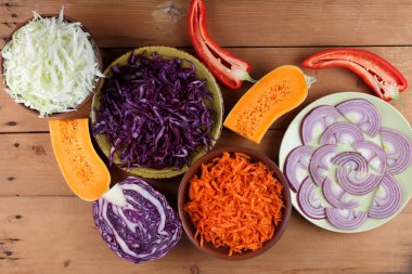 Çeşitli sebze ahşap arka plan, mor ve yeşil lahana, rendelenmiş havuç, dilimlenmiş kabak ve kırmızı biber, mor soğan yeşil bir tabak, sebzeli yemekler, sebze rustik tarzda