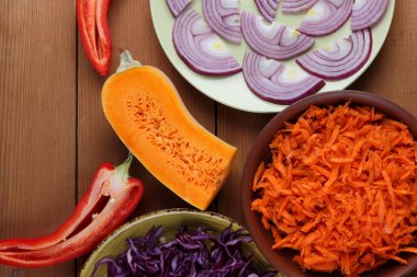 Çeşitli sebze ahşap arka plan, mor ve yeşil lahana, rendelenmiş havuç, dilimlenmiş kabak ve kırmızı biber, mor soğan yeşil bir tabak, sebzeli yemekler, sebze rustik tarzda