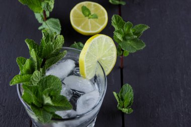 Mojito karanlık bir arka plan üzerinde yaz kokteyl limon ve nane, limon ile serinletici içecek, buz, sanat kopya alanı, minimalist kokteyl kokteyl, kutlama içmeye taze nane