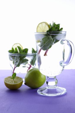 Mojito ultraviyole bir arka plan, nane, limon ve kireç, yaz dinlenmek için bir meşrubat, mor bir arka plan, bir pop sanat içki, yarım limon ve kireç, sanat bir kokteylde bir kokteyl