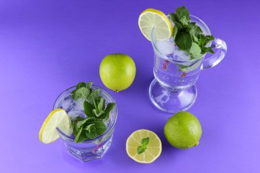 Mojito ultraviyole bir arka plan, nane, limon ve kireç, yaz dinlenmek için bir meşrubat, mor bir arka plan, bir pop sanat içki, yarım limon ve kireç, sanat bir kokteylde bir kokteyl