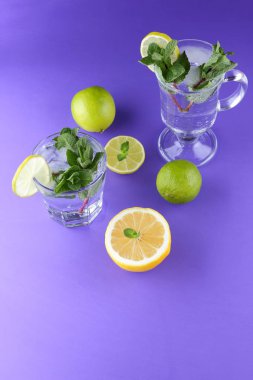 Mojito ultraviyole bir arka plan, nane, limon ve kireç, yaz dinlenmek için bir meşrubat, mor bir arka plan, bir pop sanat içki, yarım limon ve kireç, sanat bir kokteylde bir kokteyl