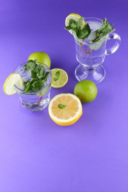 Mojito ultraviyole bir arka plan, nane, limon ve kireç, yaz dinlenmek için bir meşrubat, mor bir arka plan, bir pop sanat içki, yarım limon ve kireç, sanat bir kokteylde bir kokteyl