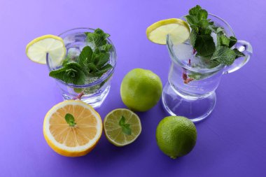 Mojito ultraviyole bir arka plan, nane, limon ve kireç, yaz dinlenmek için bir meşrubat, mor bir arka plan, bir pop sanat içki, yarım limon ve kireç, sanat bir kokteylde bir kokteyl