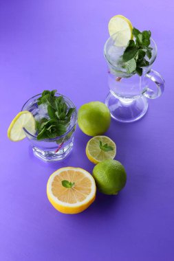 Mojito ultraviyole bir arka plan, nane, limon ve kireç, yaz dinlenmek için bir meşrubat, mor bir arka plan, bir pop sanat içki, yarım limon ve kireç, sanat bir kokteylde bir kokteyl