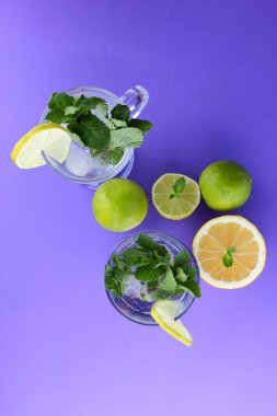 Mojito ultraviyole bir arka plan, nane, limon ve kireç, yaz dinlenmek için bir meşrubat, mor bir arka plan, bir pop sanat içki, yarım limon ve kireç, sanat bir kokteylde bir kokteyl