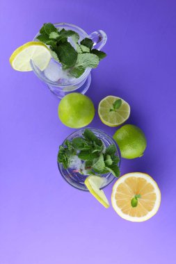Mojito ultraviyole bir arka plan, nane, limon ve kireç, yaz dinlenmek için bir meşrubat, mor bir arka plan, bir pop sanat içki, yarım limon ve kireç, sanat bir kokteylde bir kokteyl