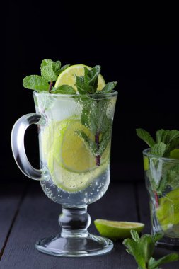 Karanlık bir arka plan üzerinde Mojito, limon ve nane, yaz kokteyl serinletici içecek içmeye kokteyl, minimalist kokteyl, kutlama buz, vegan, kopya alanı, limon, taze nane ile tasarımcı için boş