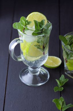 Karanlık bir arka plan üzerinde Mojito, limon ve nane, yaz kokteyl serinletici içecek içmeye kokteyl, minimalist kokteyl, kutlama buz, vegan, kopya alanı, limon, taze nane ile tasarımcı için boş