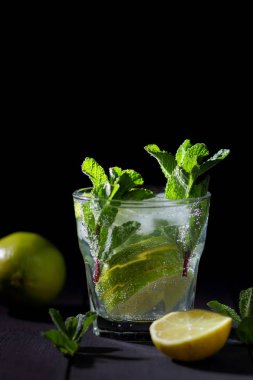 Karanlık bir arka plan üzerinde Mojito, limon ve nane, yaz kokteyl serinletici içecek içmeye kokteyl, minimalist kokteyl, kutlama buz, vegan, kopya alanı, limon, taze nane ile tasarımcı için boş