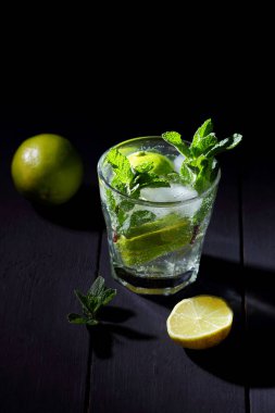 Karanlık bir arka plan üzerinde Mojito, limon ve nane, yaz kokteyl serinletici içecek içmeye kokteyl, minimalist kokteyl, kutlama buz, vegan, kopya alanı, limon, taze nane ile tasarımcı için boş