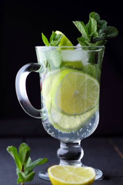 Karanlık bir arka plan üzerinde Mojito, limon ve nane, yaz kokteyl serinletici içecek içmeye kokteyl, minimalist kokteyl, kutlama buz, vegan, kopya alanı, limon, taze nane ile tasarımcı için boş