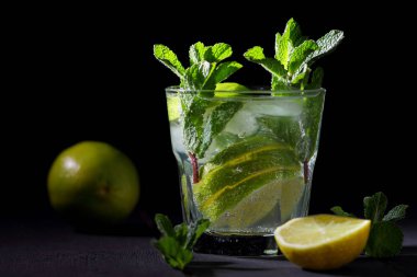 Karanlık bir arka plan üzerinde Mojito, limon ve nane, yaz kokteyl serinletici içecek içmeye kokteyl, minimalist kokteyl, kutlama buz, vegan, kopya alanı, limon, taze nane ile tasarımcı için boş