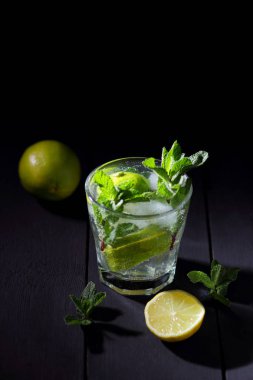Karanlık bir arka plan üzerinde Mojito, limon ve nane, yaz kokteyl serinletici içecek içmeye kokteyl, minimalist kokteyl, kutlama buz, vegan, kopya alanı, limon, taze nane ile tasarımcı için boş