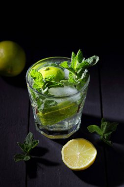 Karanlık bir arka plan üzerinde Mojito, limon ve nane, yaz kokteyl serinletici içecek içmeye kokteyl, minimalist kokteyl, kutlama buz, vegan, kopya alanı, limon, taze nane ile tasarımcı için boş