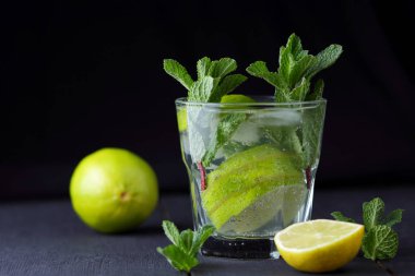 Karanlık bir arka plan üzerinde Mojito, limon ve nane, yaz kokteyl serinletici içecek içmeye kokteyl, minimalist kokteyl, kutlama buz, vegan, kopya alanı, limon, taze nane ile tasarımcı için boş