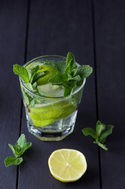 Karanlık bir arka plan üzerinde Mojito, limon ve nane, yaz kokteyl serinletici içecek içmeye kokteyl, minimalist kokteyl, kutlama buz, vegan, kopya alanı, limon, taze nane ile tasarımcı için boş