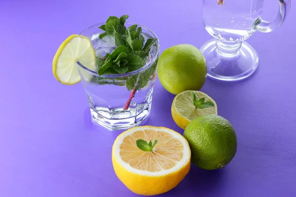 Mojito ultraviyole bir arka plan, nane, limon ve kireç, yaz dinlenmek için bir meşrubat, mor bir arka plan, bir pop sanat içki, yarım limon ve kireç, sanat bir kokteylde bir kokteyl