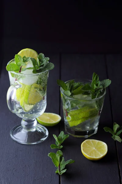 Karanlık bir arka plan üzerinde Mojito, limon ve nane, yaz kokteyl serinletici içecek içmeye kokteyl, minimalist kokteyl, kutlama buz, vegan, kopya alanı, limon, taze nane ile tasarımcı için boş
