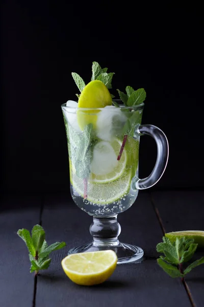 Mojito on a dark background, summer cocktail with lime and mint, refreshing drink with lemon, fresh mint for cocktail, minimalist cocktail, celebratory drink with ice, vegan, copy space, blank for designer