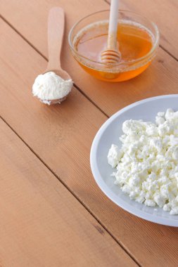Peynir, taze peynir beyaz tabak, tahta kaşık, süzme peynir ve bal bir ahşap arka plan, bir tahta kaşık ekşi krema, süt ve süt ürünleri doğal arka plan, retro tarzı, minimalizm, Fransız Kahvaltı