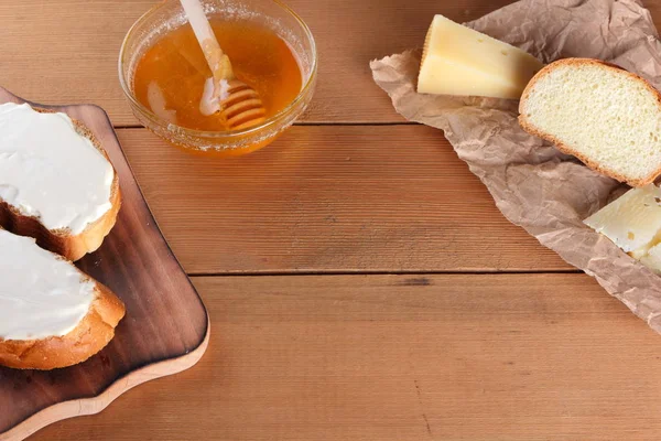 Ahşap oyun tahtası, parşömen kağıt, gıda sert peynir yumuşak peynir ile bal cam yemekleri, kopya alanı, peynir desen, ahşap arka plan, ahşap çatal bıçak takımı, basit gıda sandviç.