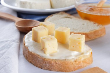 Peynir beyaz bir tabak, bardak yoğurt, peynir, minimalizm, üstten görünüm, kopya bir sandviçle alanı, bir parça ekmek sert peynir, mavi bir bez, Fransız Kahvaltı, beyaz bir arka plan üzerinde beyaz peynir ile