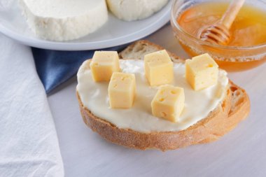 Peynir beyaz bir tabak, bardak yoğurt, peynir, minimalizm, üstten görünüm, kopya bir sandviçle alanı, bir parça ekmek sert peynir, mavi bir bez, Fransız Kahvaltı, beyaz bir arka plan üzerinde beyaz peynir ile