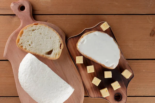 Cheese, a sandwich with soft cheese, hard cheese on a wooden board, minimalism, wooden cutlery, honey, kefir in a glass, copy space, a piece of bread, cheese, cheese pattern, French breakfast