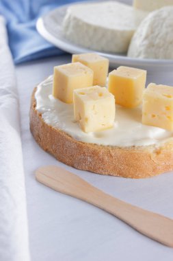 Beyaz peynir, beyaz bir arka planda bir mavi peçete, ahşap arka plan, ahşap çatal bıçak takımı, üstten görünüm, yumuşak peynirli sandviç süt ürün yelpazesine peynir beyaz tabakta kefir bir cam, pop art