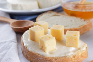 Peynir ve bal beyaz bir tabak, kefir, yumuşak peynir, minimalizm, tatlım, bir parça ekmek, mavi peçete ile bir sandviç, Fransız beyaz bir arka plan üzerinde Amerikan mutfağı Servis Kahvaltı