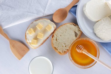 Peynir ve bal beyaz bir tabak, kefir, yumuşak peynir, minimalizm, tatlım, bir parça ekmek, mavi peçete ile bir sandviç, Fransız beyaz bir arka plan üzerinde Amerikan mutfağı Servis Kahvaltı