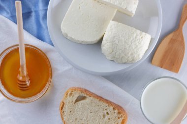 Peynir ve bal beyaz bir tabak, kefir, yumuşak peynir, minimalizm, tatlım, bir parça ekmek, mavi peçete ile bir sandviç, Fransız beyaz bir arka plan üzerinde Amerikan mutfağı Servis Kahvaltı