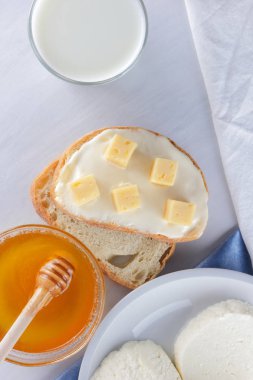 Peynir ve bal beyaz bir tabak, kefir, yumuşak peynir, minimalizm, tatlım, bir parça ekmek, mavi peçete ile bir sandviç, Fransız beyaz bir arka plan üzerinde Amerikan mutfağı Servis Kahvaltı