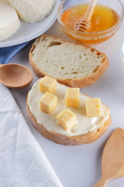 Peynir ve bal beyaz bir tabak, kefir, yumuşak peynir, minimalizm, tatlım, bir parça ekmek, mavi peçete ile bir sandviç, Fransız beyaz bir arka plan üzerinde Amerikan mutfağı Servis Kahvaltı